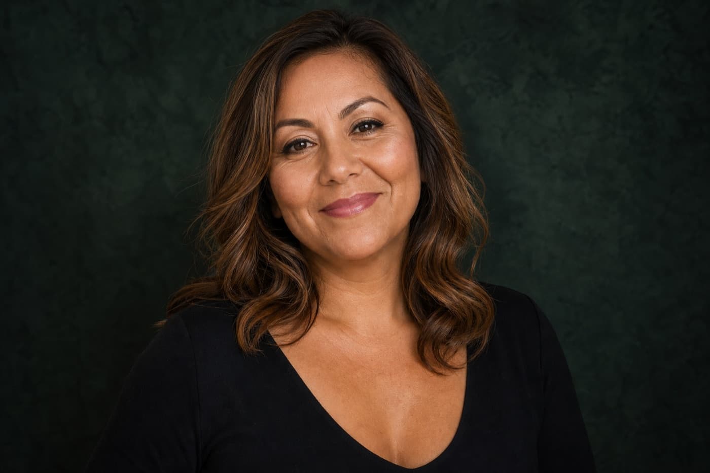 Confident woman in a forest green studio portrait, Xenith Health wellness